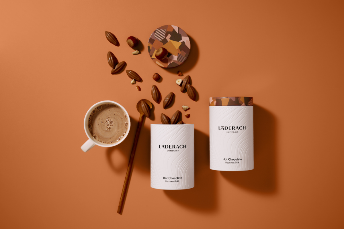 Hazelnut milk hot chocolate, chocolate drops and hazelnuts on an orange background